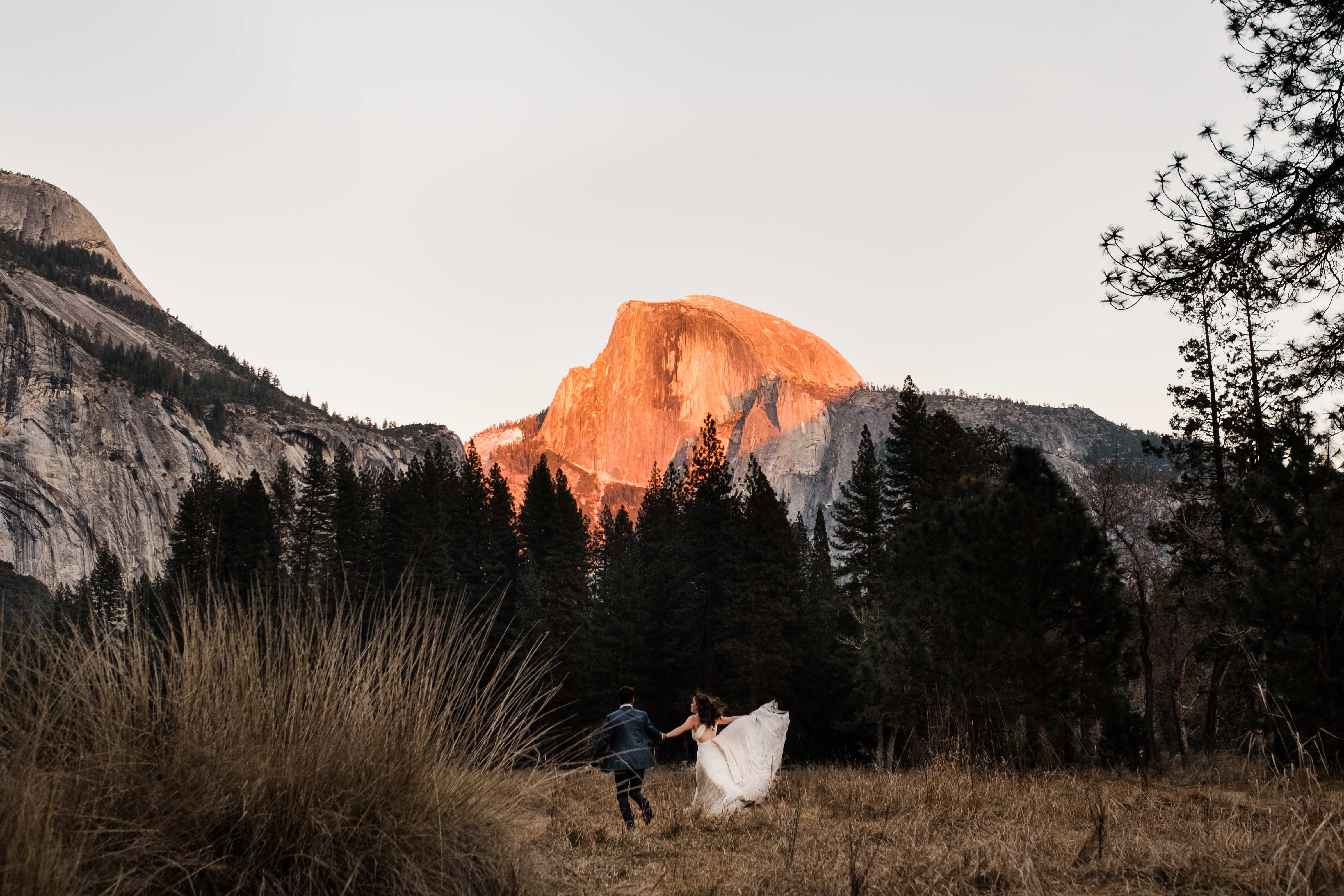 Half Dome gleams with fiery sunlight as the sun sets on Ryan and Kim's adventure elopement session in the Yosemite Valley.